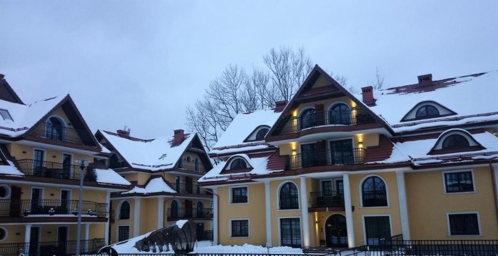 a large yellow house with snow on its roof at Apartamenty-Plaza Zakopane in Zakopane