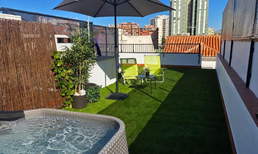 a balcony with an umbrella and chairs on a roof at Departamento en Fuengirola-Cerca del mar in Fuengirola