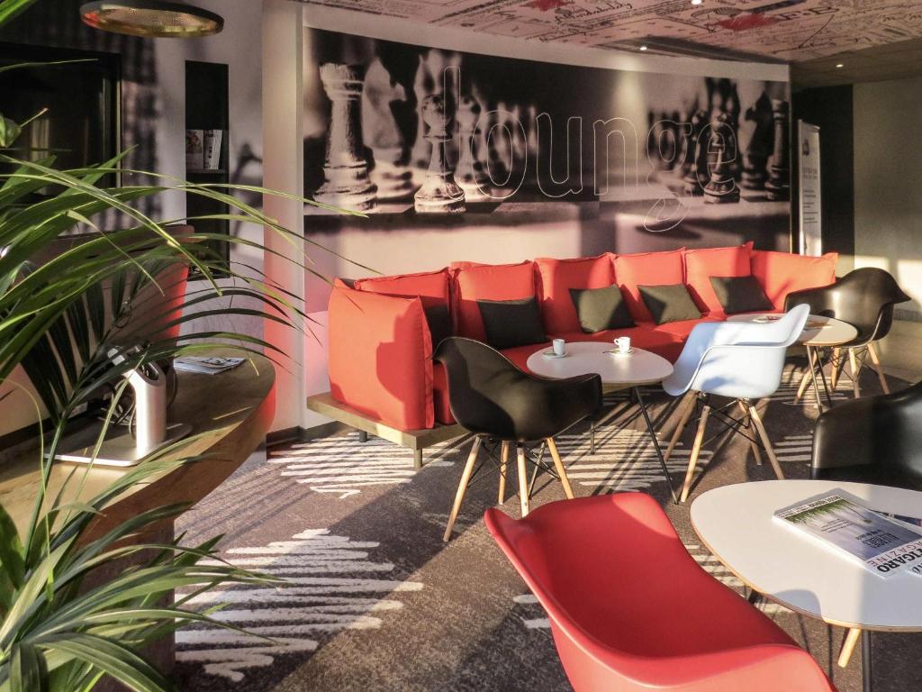 a restaurant with red and black chairs and tables at ibis Soissons in Soissons
