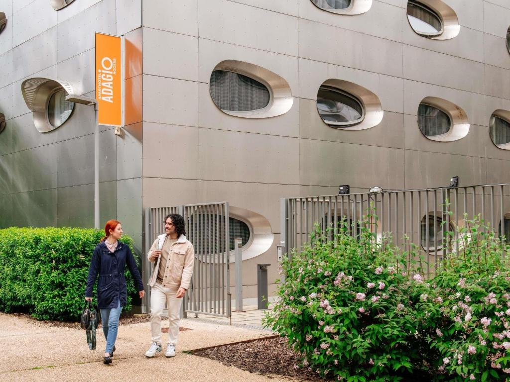 two women walking down a sidewalk in front of a building at Aparthotel Adagio Access Nancy Centre in Nancy
