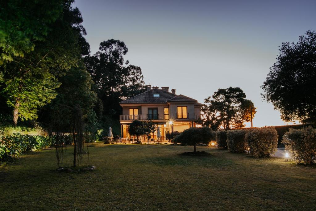 a large house sitting on top of a lush green yard at Hotel EntreRobles in Baiona