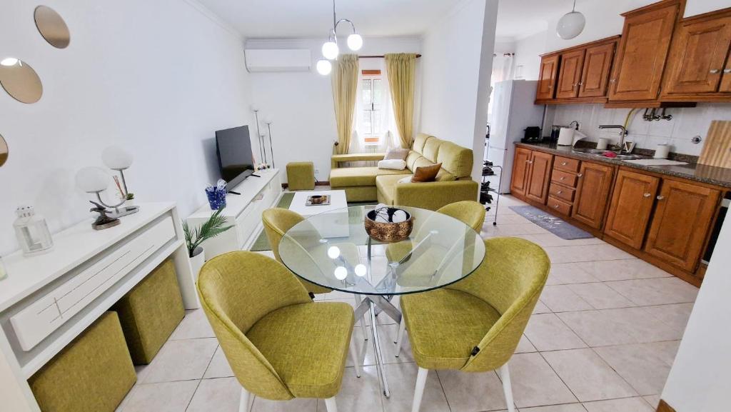 eine Küche und ein Wohnzimmer mit einem Glastisch und Stühlen in der Unterkunft Cocoon pour 6 personnes in Mirandela