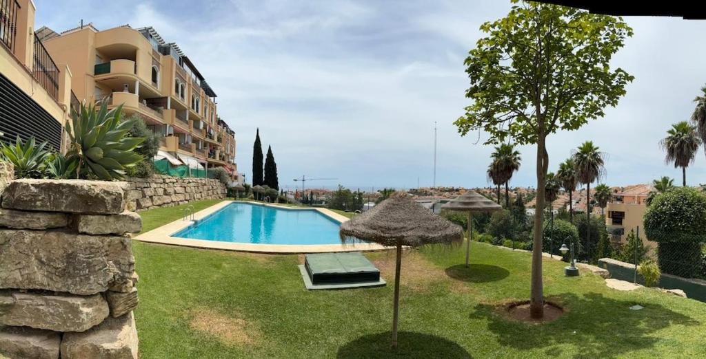 a swimming pool in a yard next to a building at A spacious apartment with an ocean view in Mijas Costa