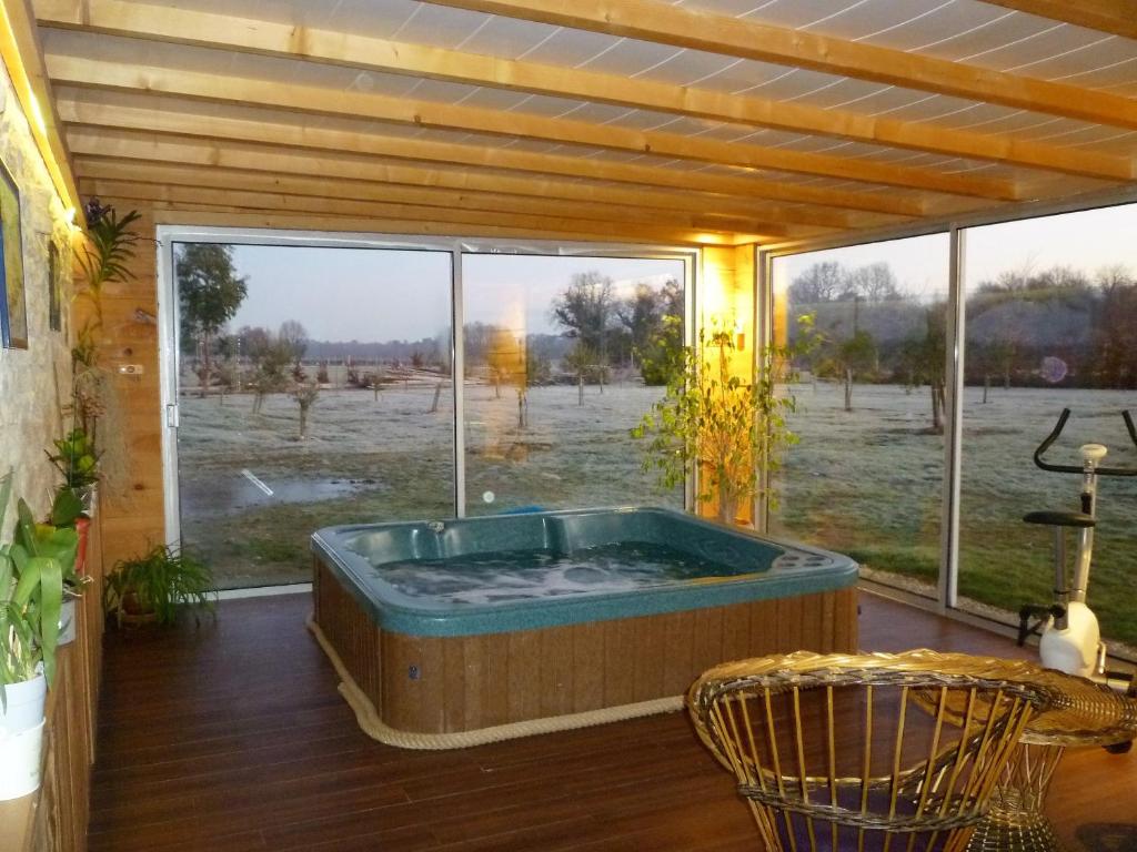 een hot tub in een kamer met een groot raam bij La SERPAUDERIE in Saint-André-de-Lidon