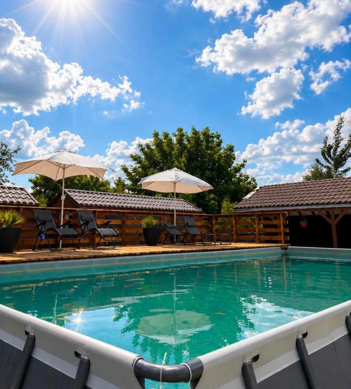 a swimming pool with chairs and umbrellas at Holiday Resort Zakątek Łeba in Łeba
