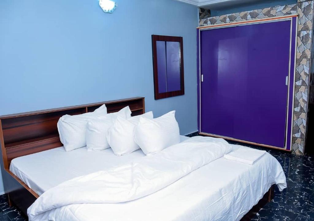 a bedroom with two white beds with a purple wall at Luxury Deluxe 1 Bed, 1 Bath in Otta