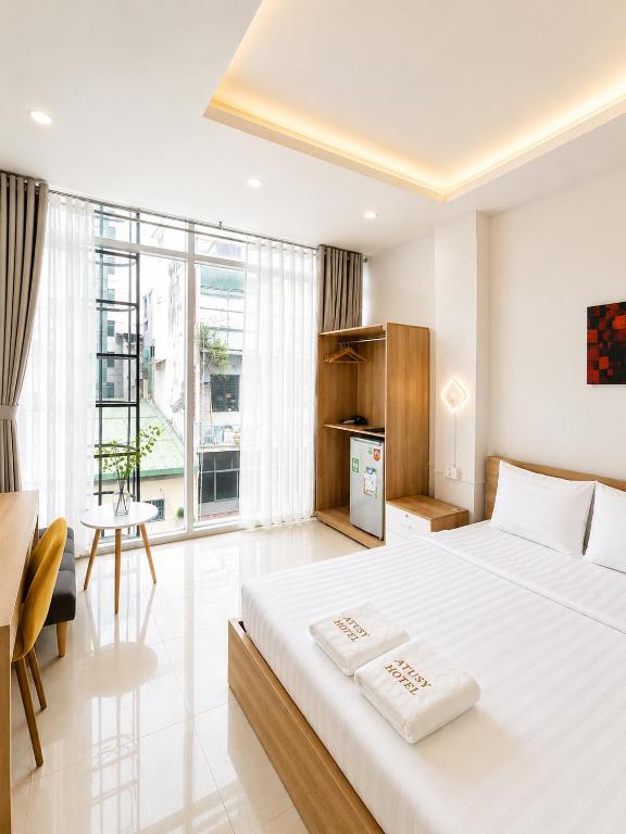 a bedroom with a large white bed and a large window at Atusy Hotel in Ho Chi Minh City