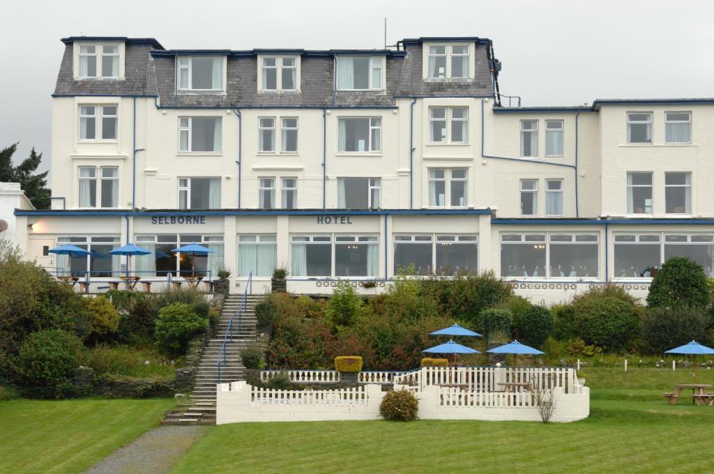 un grand bâtiment blanc avec des parasols bleus devant lui dans l'établissement Selborne Hotel, à Dunoon