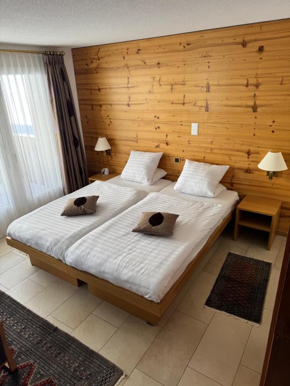 a bedroom with a large bed with a wooden wall at Cozy Studio with Wellness in Goms in Blitzingen