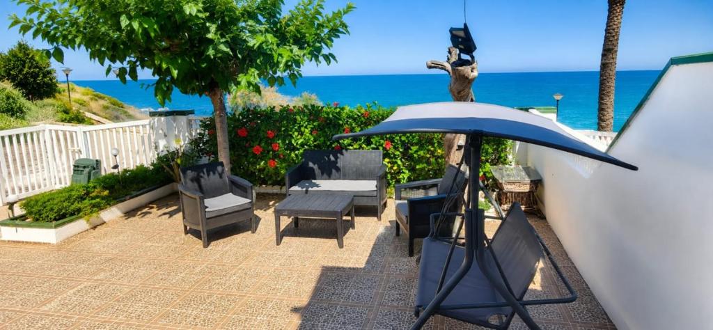 a patio with chairs and an umbrella and the ocean at Akimaria Residence in Oropesa del Mar