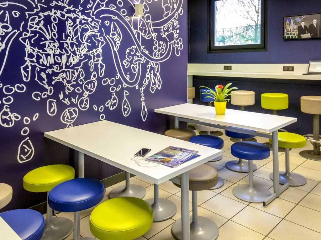 a waiting room with two tables and colorful stools at ibis budget Vienne Sud in Vienne