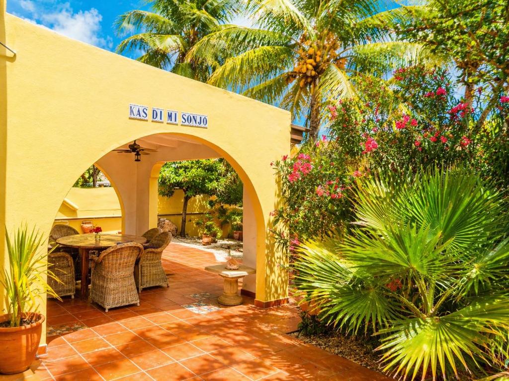 a patio with a table and chairs and palm trees at 30 Kas Di Mi Sonjo in Kralendijk