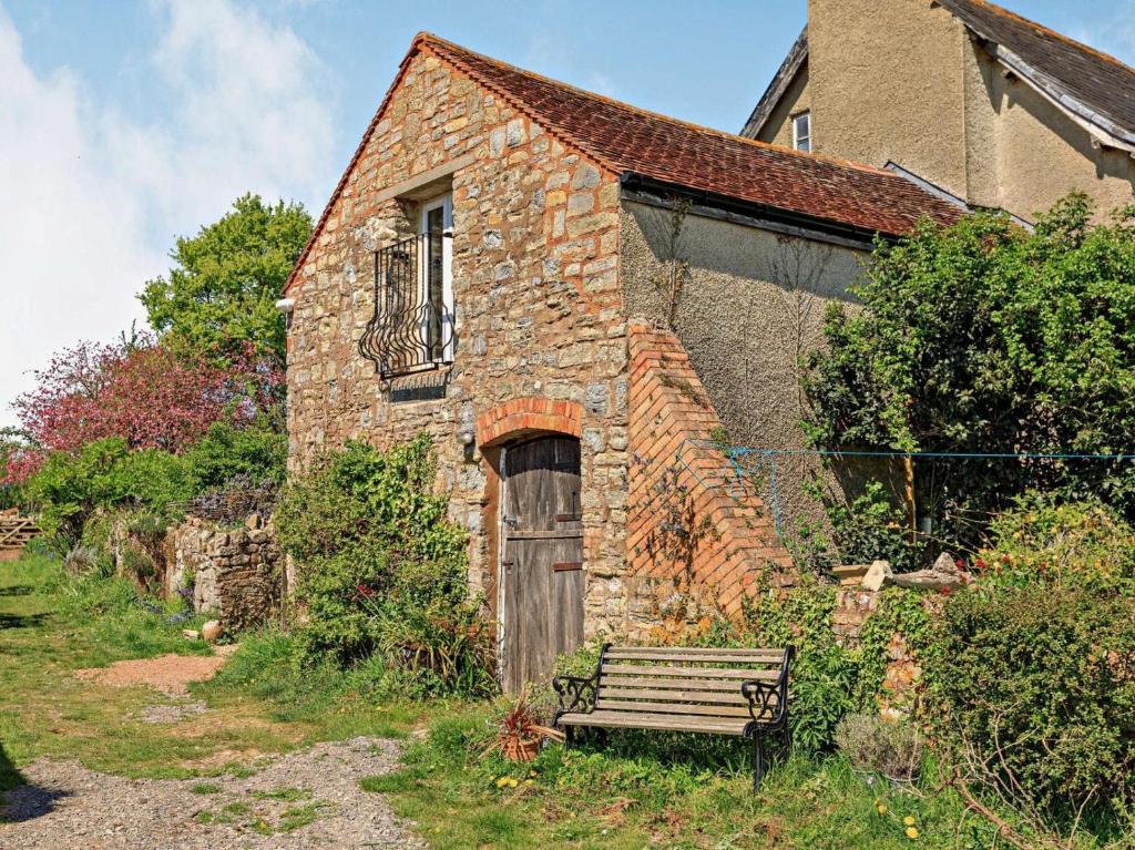 an old stone house with a bench in front of it at 1 Bed in Taunton oc-87929 in Pitminster