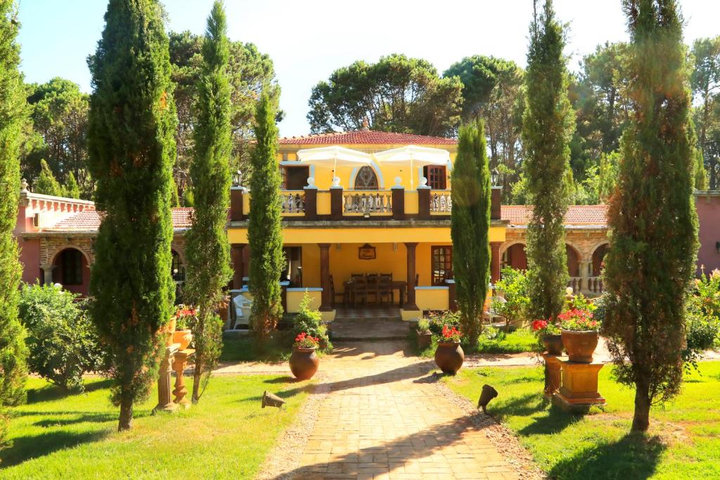 una grande casa gialla con balcone e alberi di Villa Toscana Boutique Hotel -Adults Only a Punta del Este
