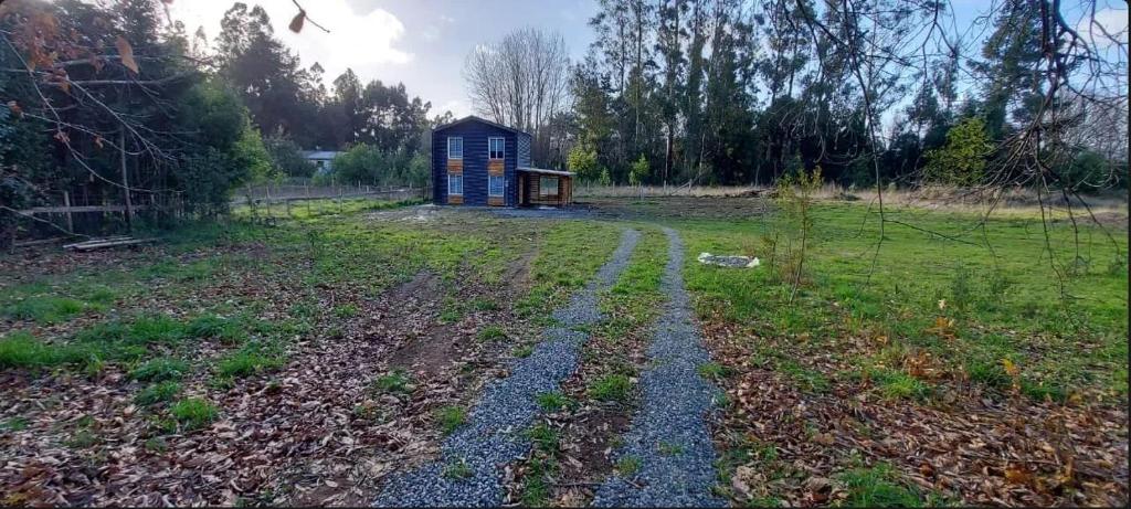 a small house in a field with a dirt road at Sendero de Luna in Valdivia