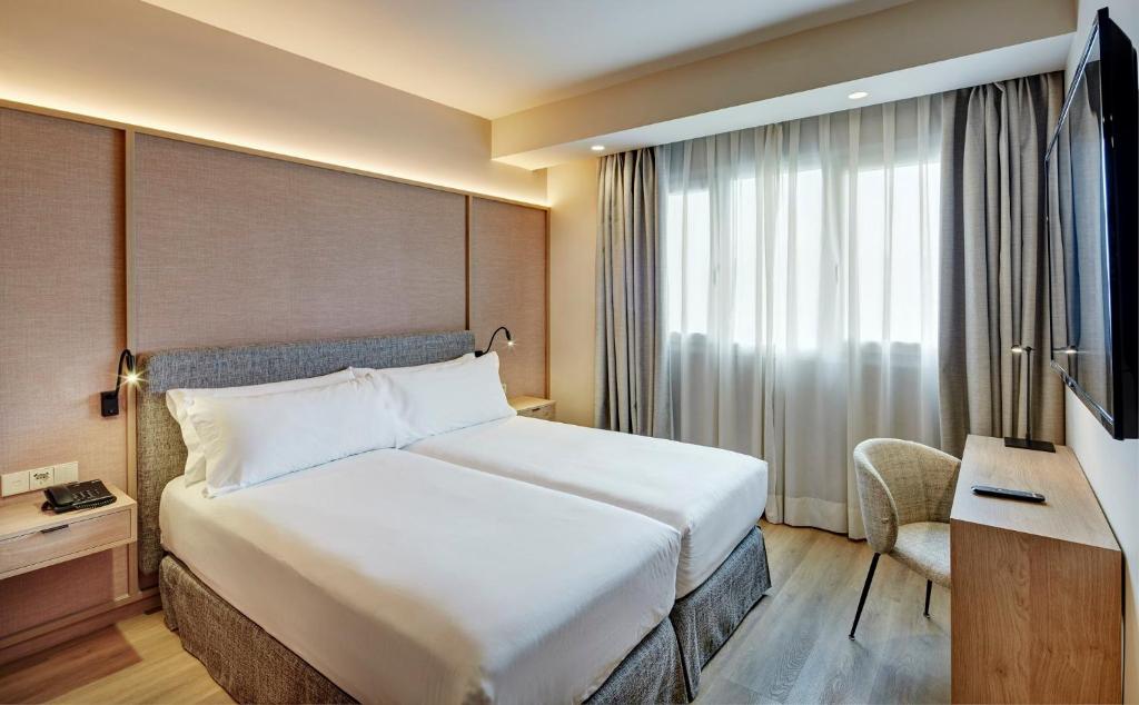a hotel room with a large bed and a television at Sercotel Pozuelo in Pozuelo de Alarcón