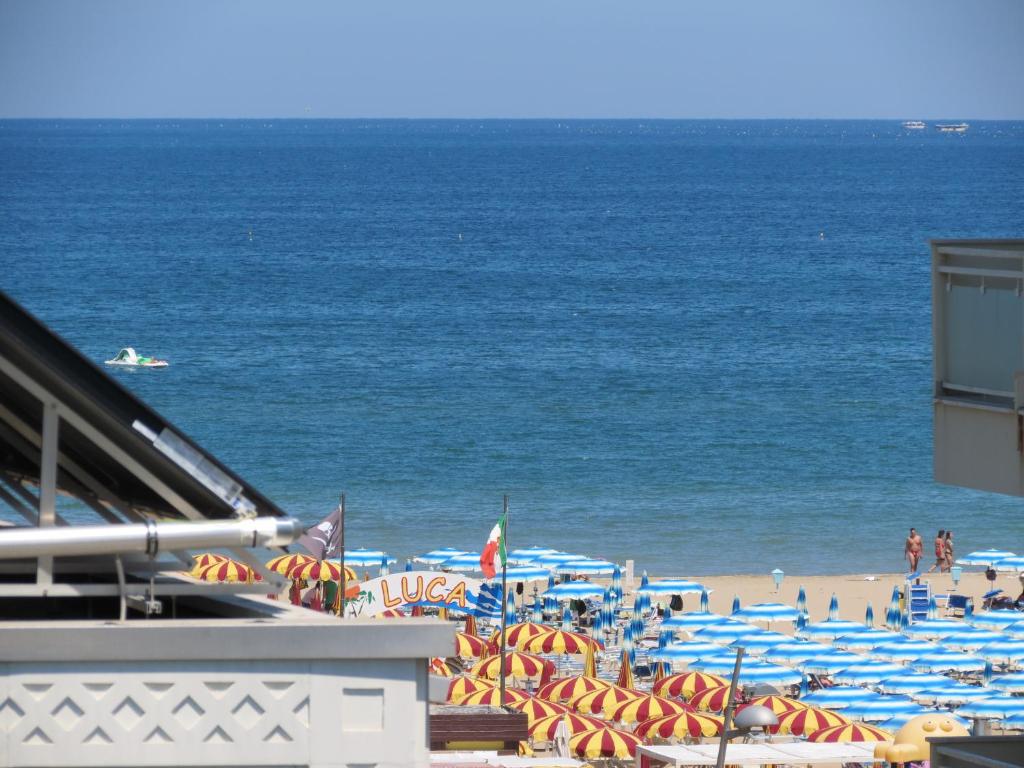 una spiaggia con ombrelloni blu e arancione e l'oceano di Hotel Gemini a Rimini