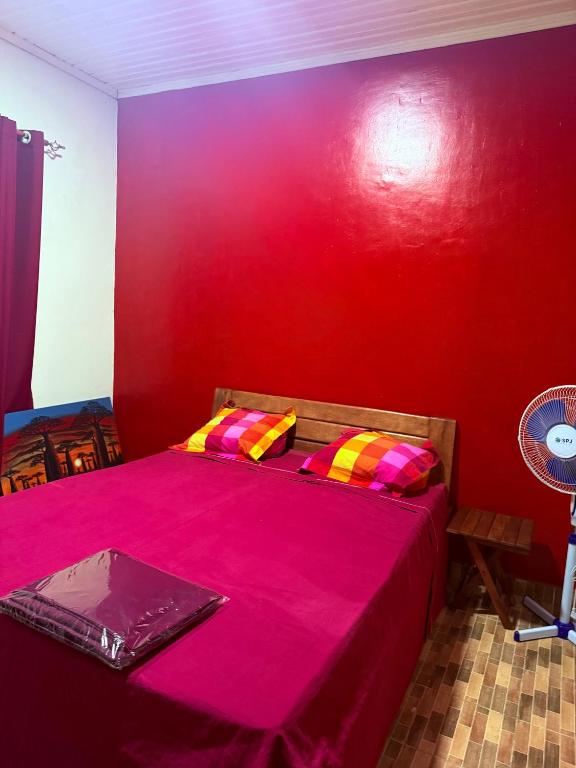 a red room with a bed with a red wall at Logis Baobab in Morondava