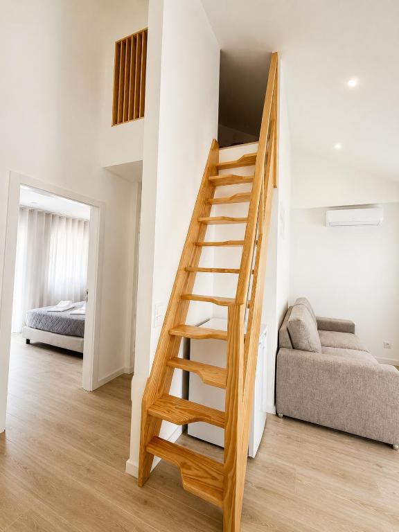 a wooden staircase in a white room with a bed at Casa do Leme in Nazaré