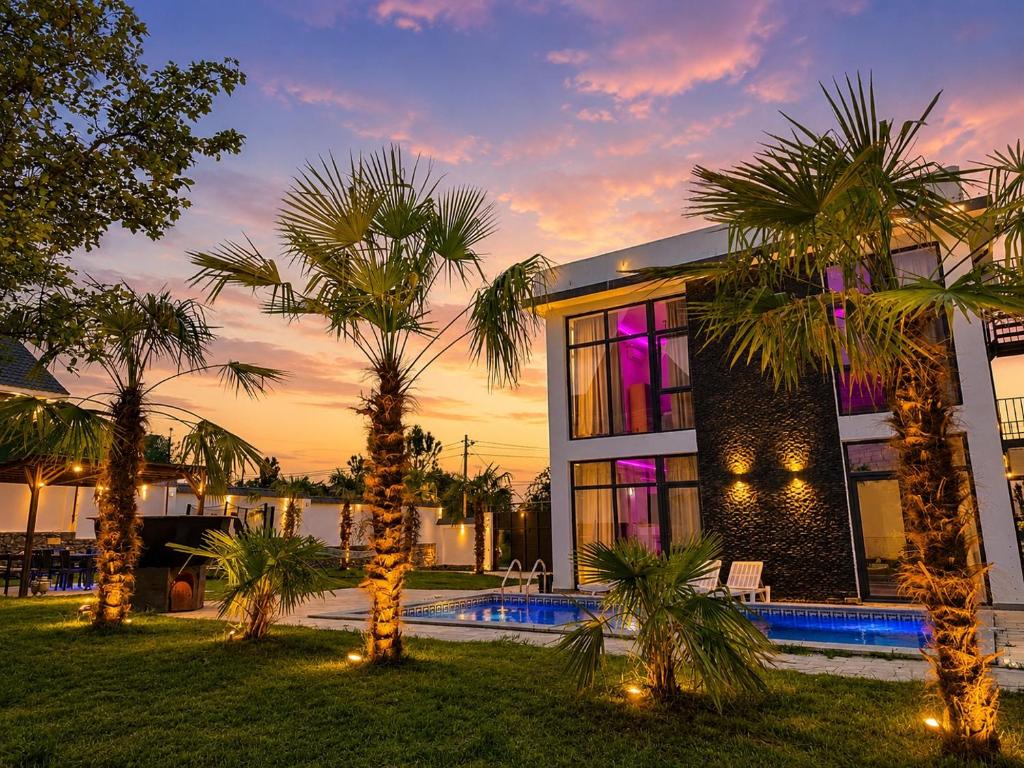 a house with palm trees in front of it at Qafqaz Mandarin Deluxe in Gabala