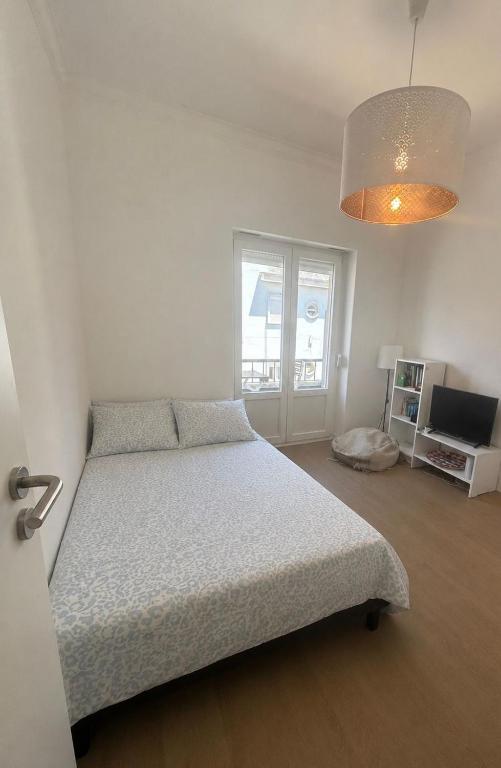 a white bedroom with a bed and a television at Quarto 15 min de Lisboa in Amadora