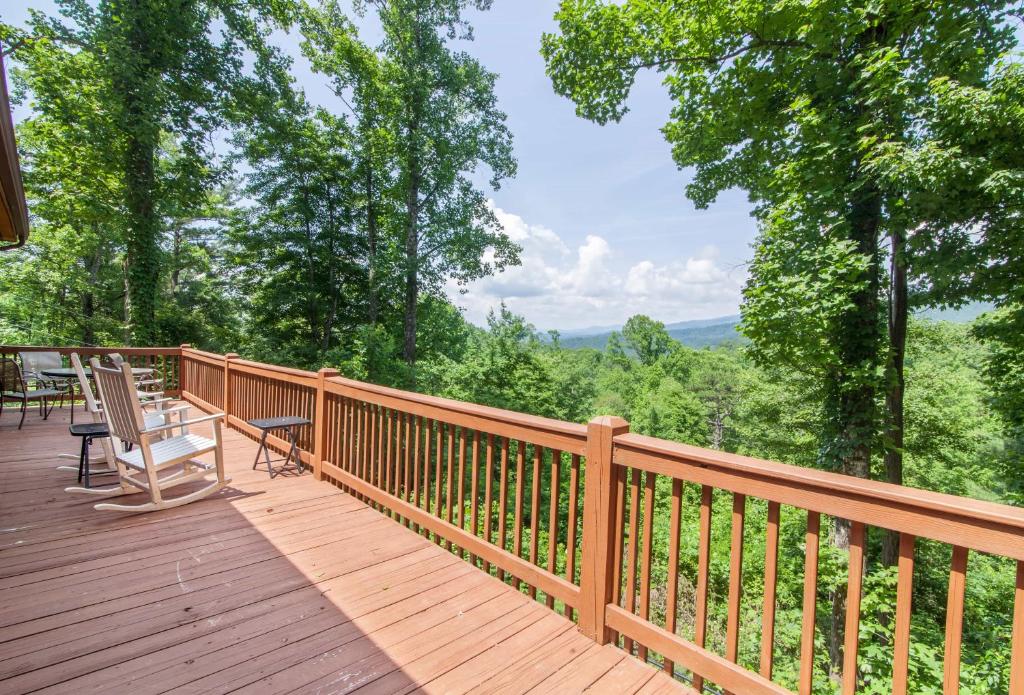 a wooden deck with chairs and a table on it at Misty Mountain Cabin in Lenoir