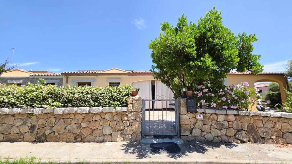 a house with a stone fence and a tree at Villa Angedras in San Teodoro