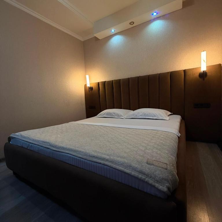 a bed in a room with two lights on the wall at Three Star in Almaty