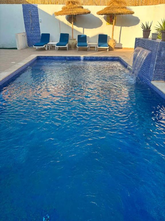 a large swimming pool with blue chairs and umbrellas at Drams in Mezraya