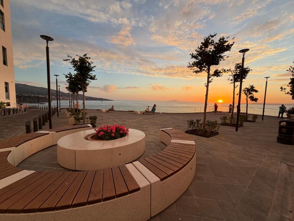 a park with benches and a sunset on the beach at Lauro Apartment in Meta