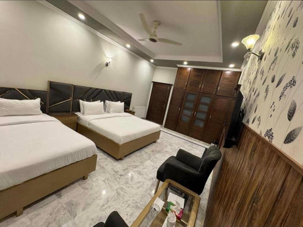 a hotel room with two beds and a chair at Galaxy Family Hotel Karachi Airport in Karachi