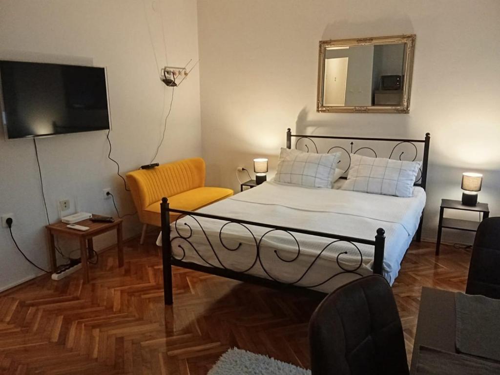 a bedroom with a bed and a chair and a television at Studio apartman LUNA in Vinkovci