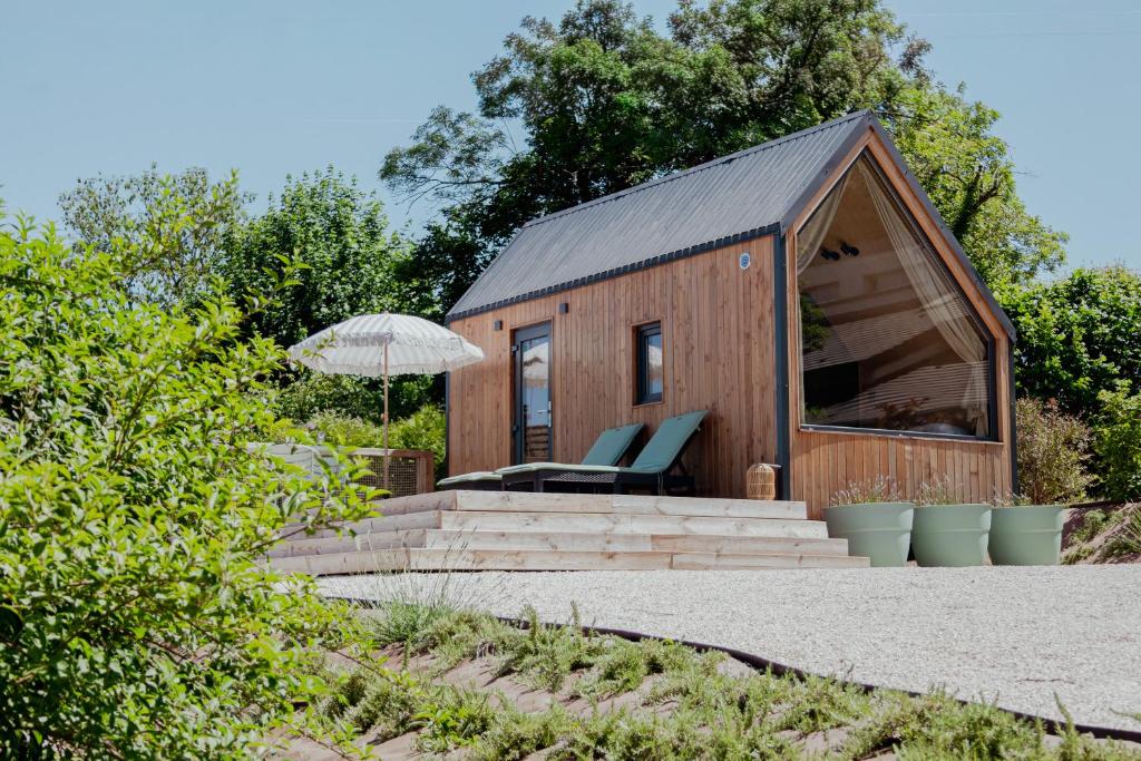 a small wooden cabin with a chair and an umbrella at Tiny House - Nature&calme - Pétanque&barbecue in Quincey