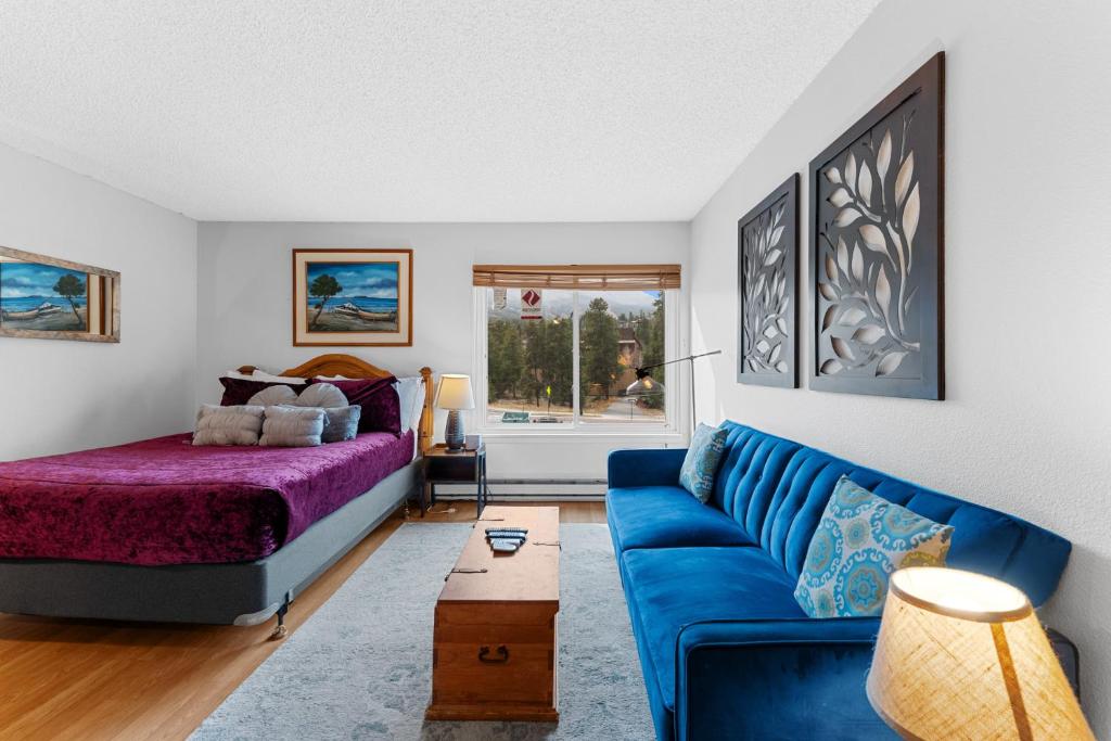 a living room with a blue couch and a bed at Blazing Saddles #102 in Breckenridge