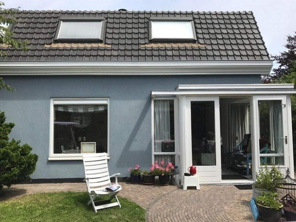 a blue house with a porch and a white chair at Holiday Home Noordwijk near Beach & Sauna in Noordwijk