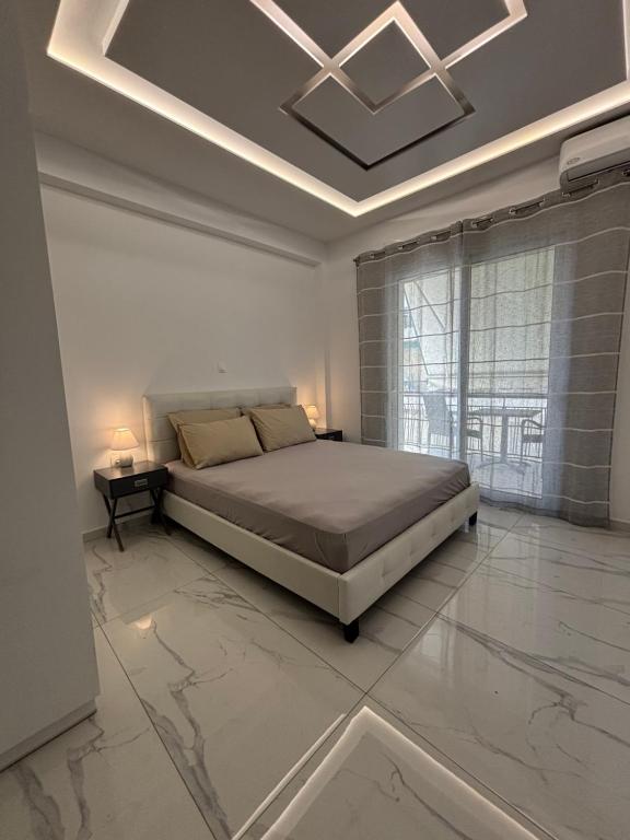 a white bedroom with a bed and a large window at The Onyx Residence in Loutraki