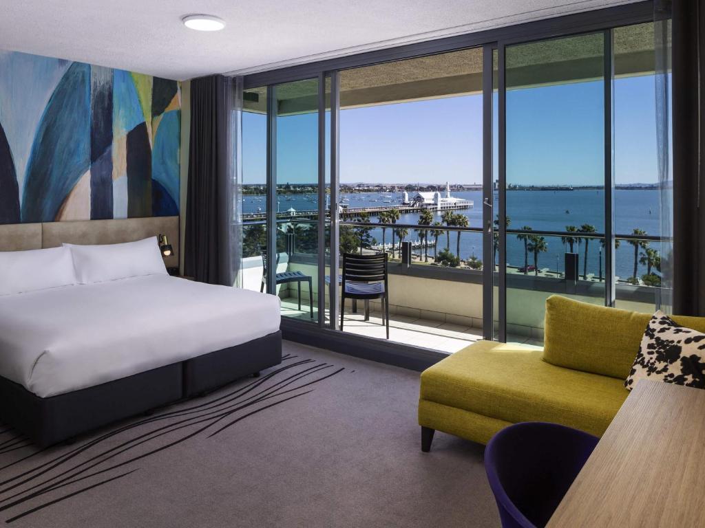 a hotel room with a bed and a view of the water at Novotel Geelong in Geelong