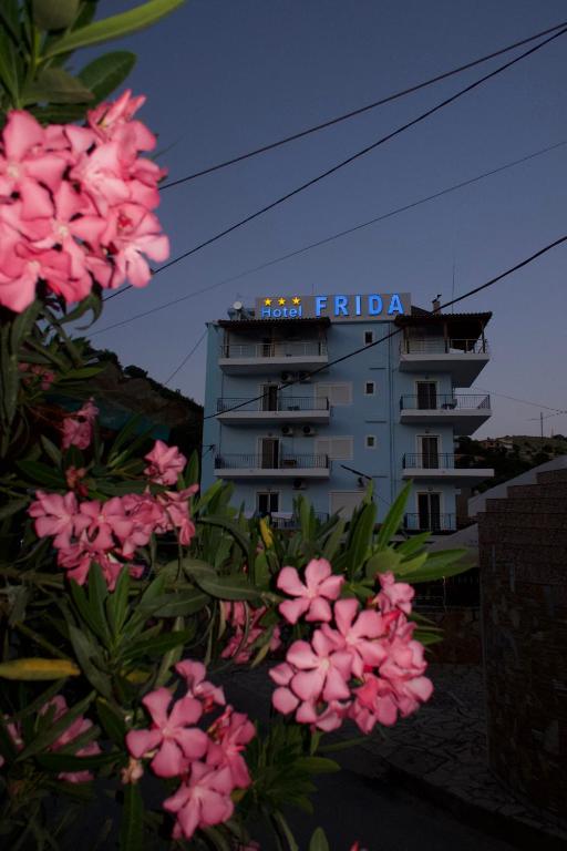 a building with a sign on it in front of pink flowers at Hotel Frida in Himare