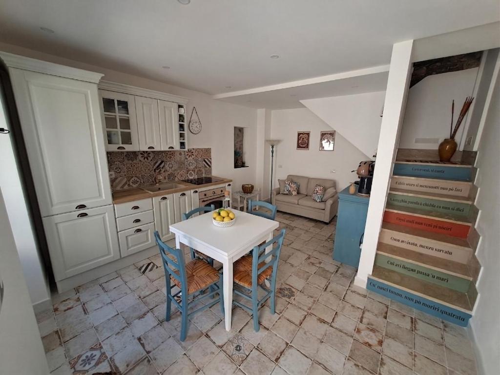 a kitchen with a white table and chairs and a staircase at Gredò Home & SPA in Gratteri