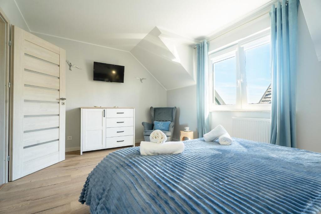 a bedroom with a blue bed and a window at Apartamenty Lagos in Karwia
