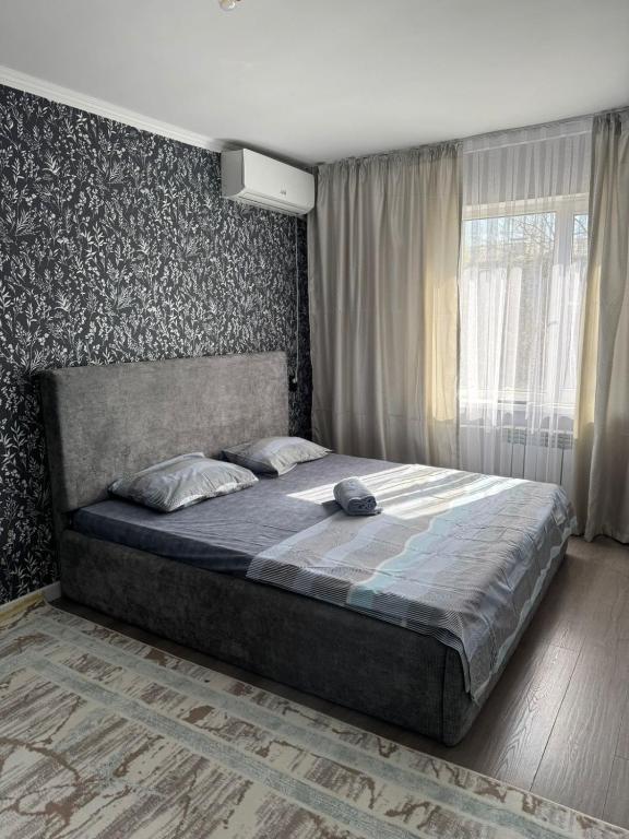 a bedroom with a large bed in front of a window at Apartments Aibergenova 4 in Shymkent