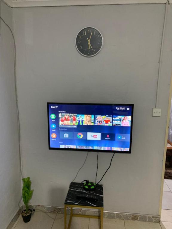 a flat screen tv on a wall with a clock at 399 Place in Umtali