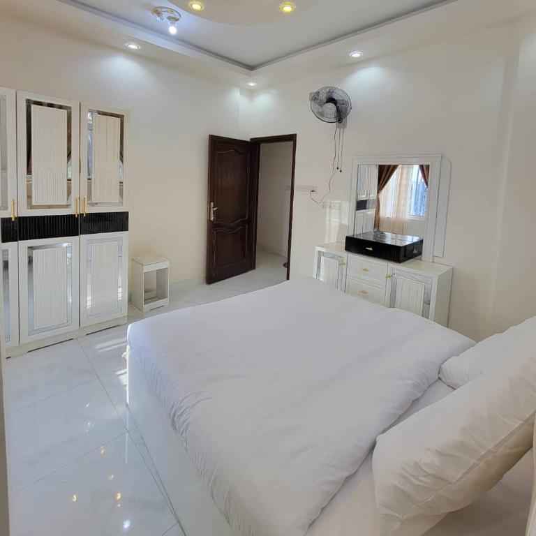 a white bedroom with a large bed and a television at ألعز in Qaḩāzah