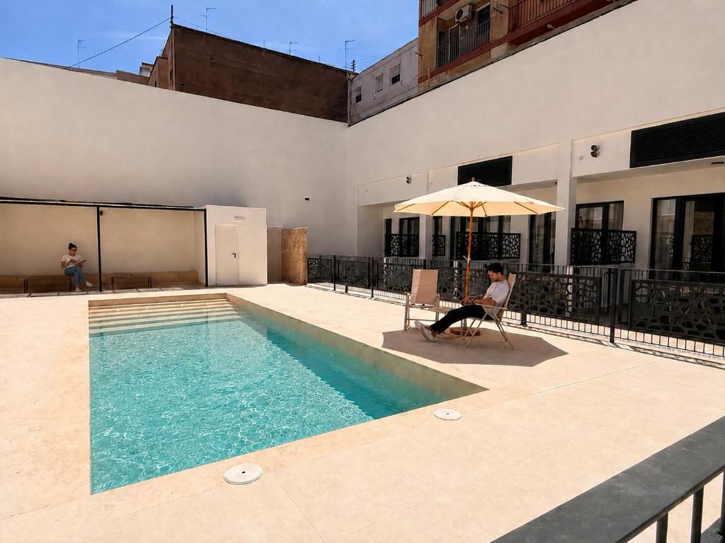 a woman sitting in a chair next to a swimming pool at Maritime Coliving Valencia in Valencia