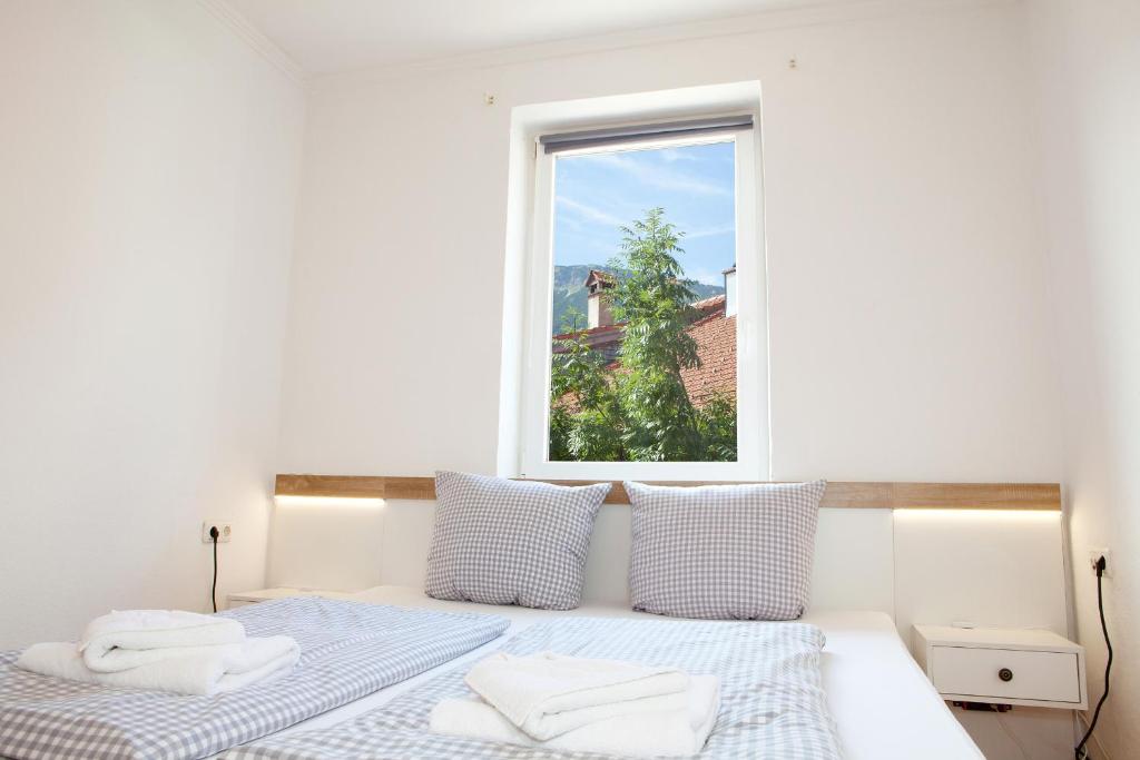 a white bedroom with two beds and a window at Dorfwirt Pfronten in Pfronten