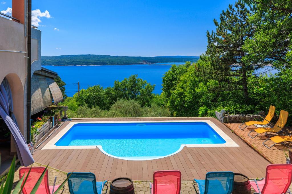 a swimming pool with chairs and a view of the water at Apartments Djusi in Dramalj