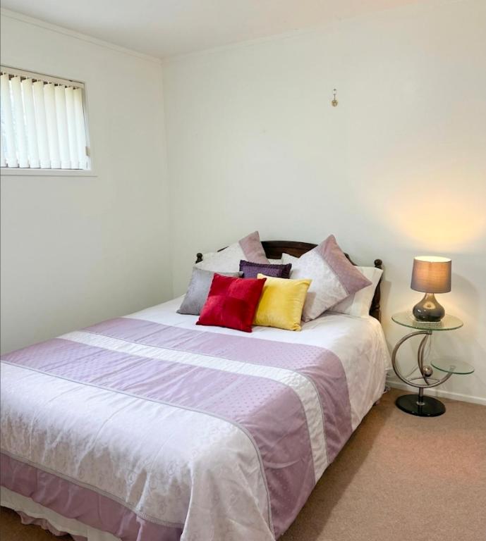 a bedroom with a large bed with colorful pillows at Private 2-Bedroom Suite in 3-Bedroom House in Auckland