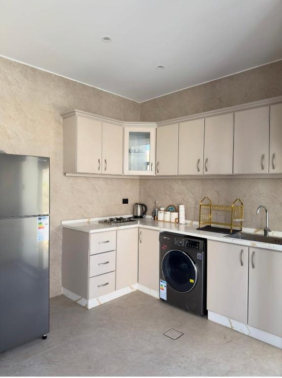 a kitchen with white cabinets and a washer and dryer at Royal Pearl Villa 1 in Sowayma