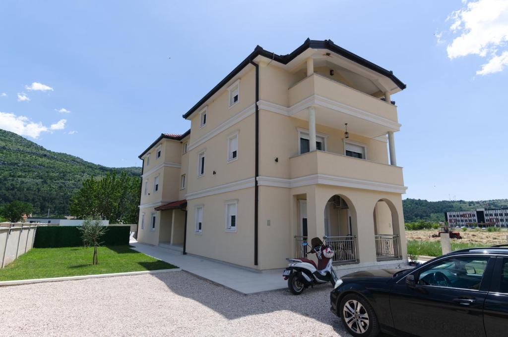 una donna seduta su uno scooter davanti a una casa di Vila Magdalena a Trebinje