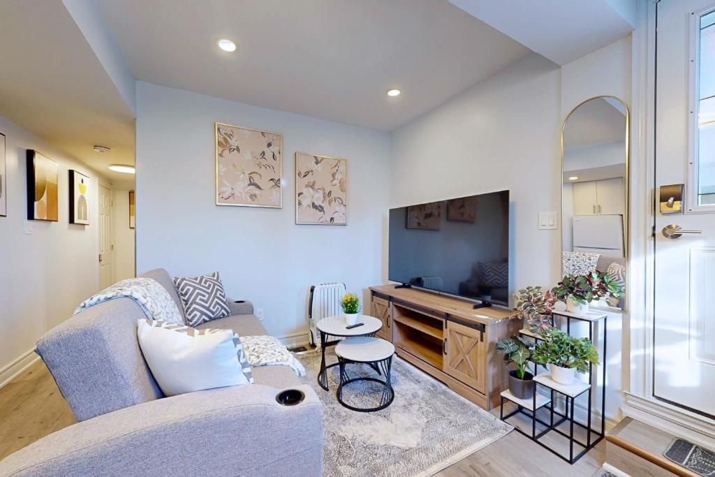 a living room with a couch and a tv at New & Modern Basement Suite - St Clair Hotel in Toronto